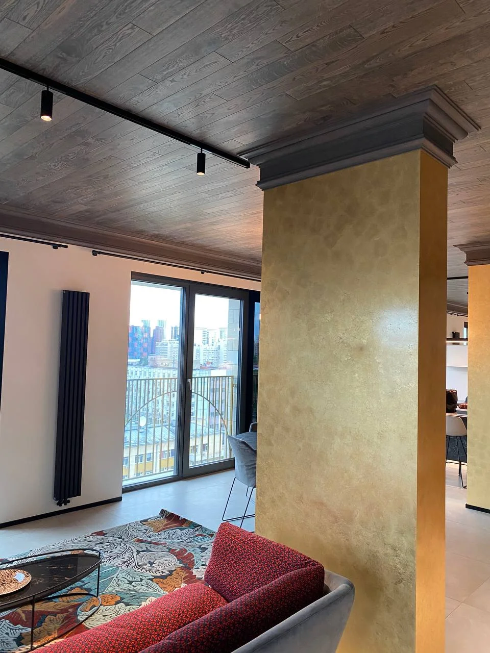 Золотая колонна, диван, ковёр, город за окном