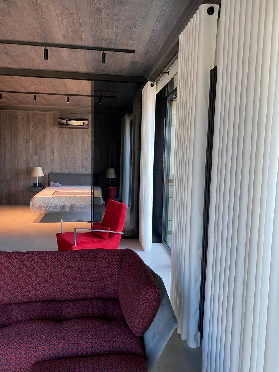 Диван и спальня за стеклянной стеной